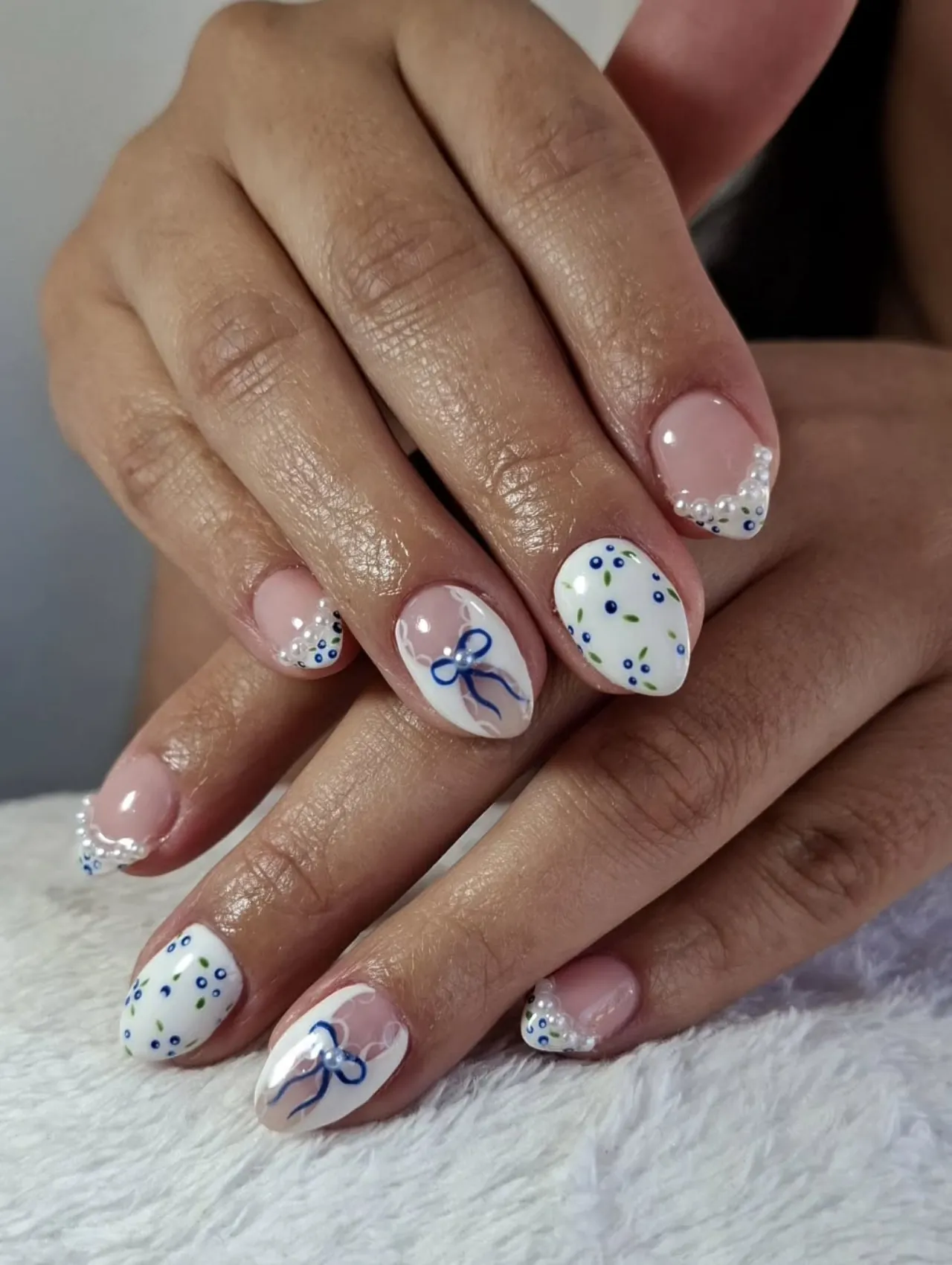 Diseños de uñas para invierno con francesa azul, lazos y perlas
