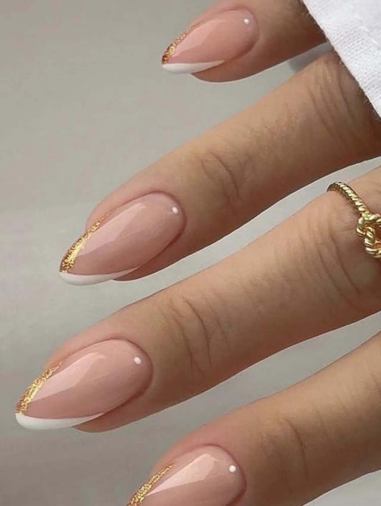 Diseños de uñas para invierno con francesa blanca y dorada con detalle minimalista
