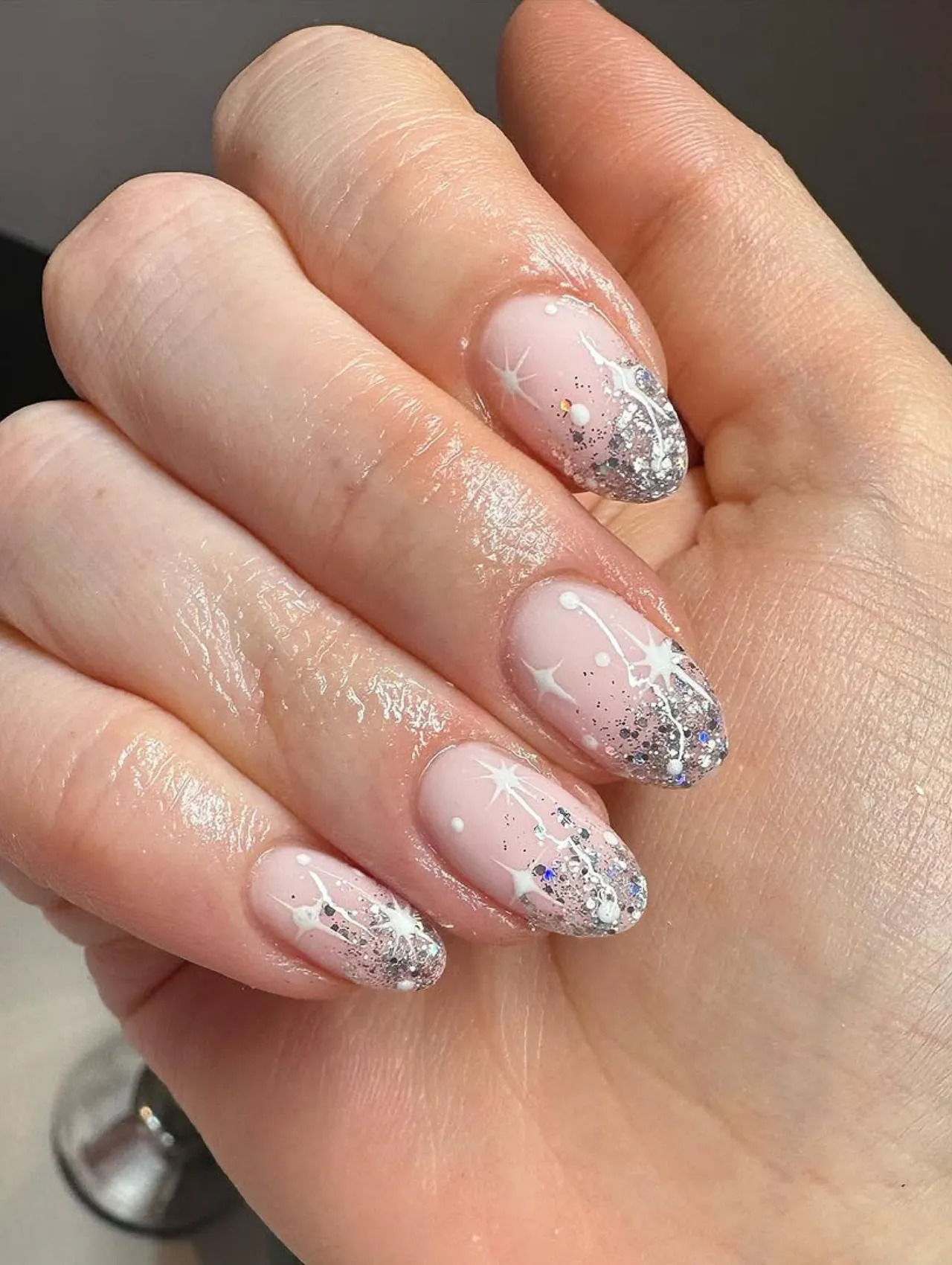 Diseños de uñas para invierno con glitter plateado y estrellas blancas
