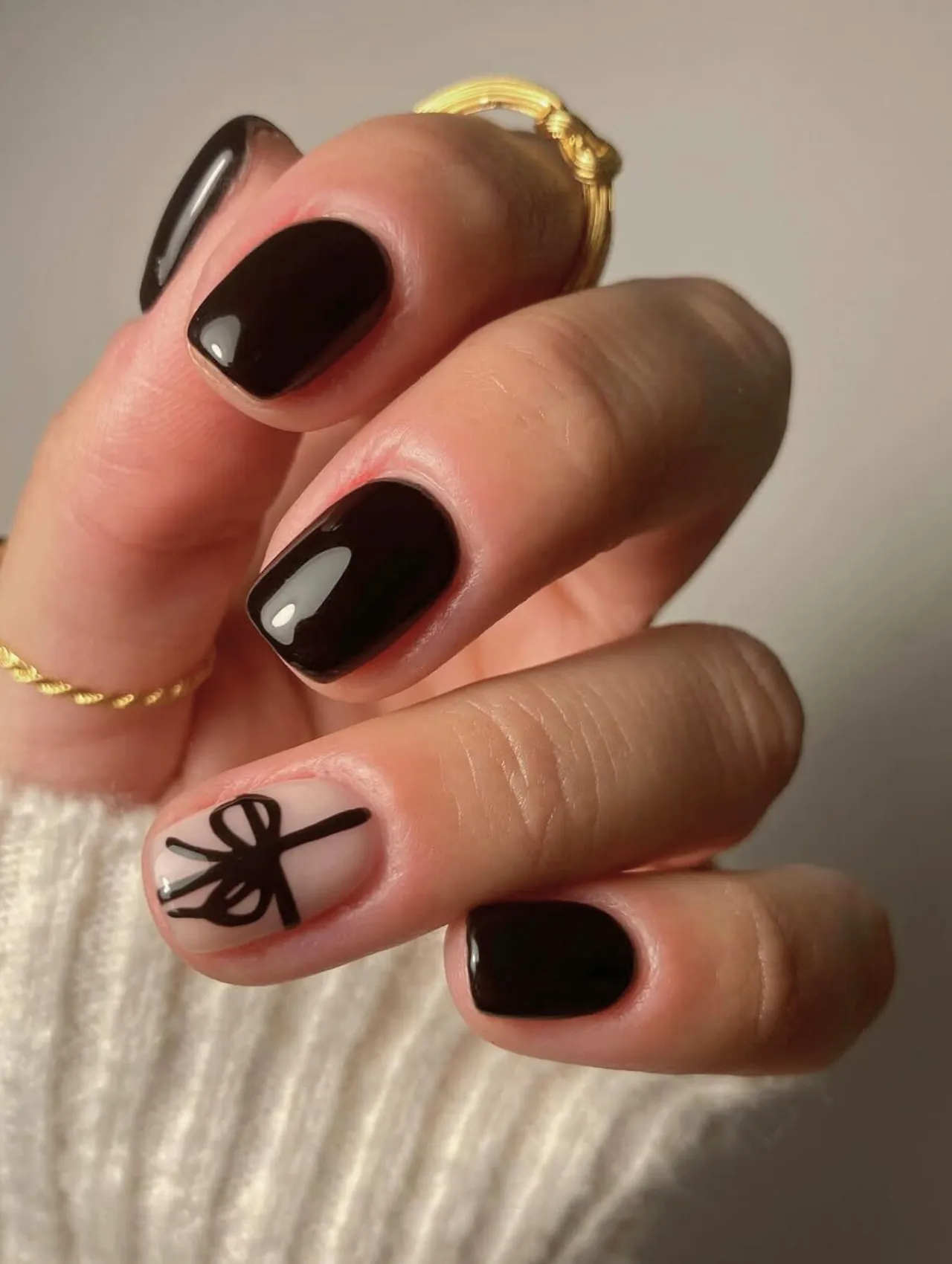 Diseños de uñas para invierno con lazo negro en uñas cortas elegantes