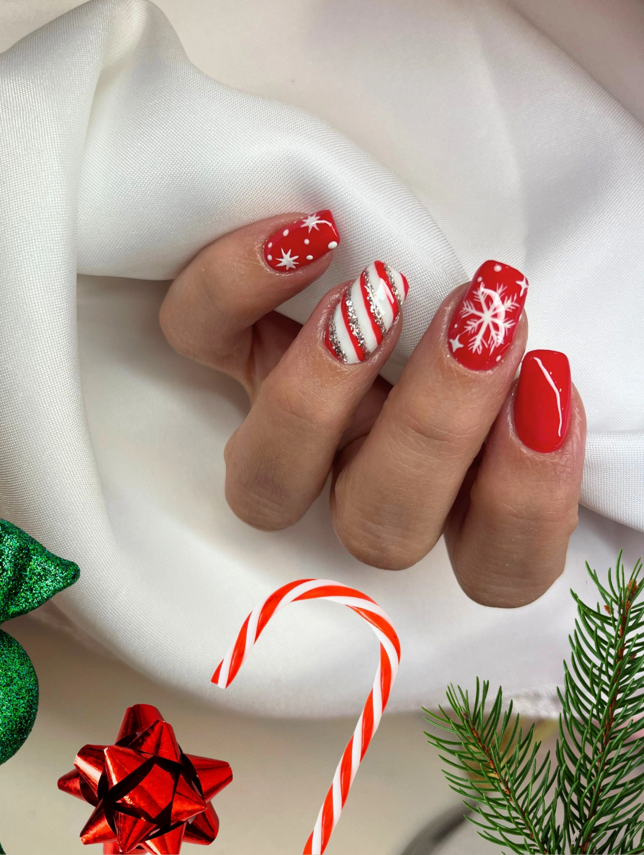 Candy Cane Christmas Nails with red polish, snowflakes, and striped peppermint accent design.