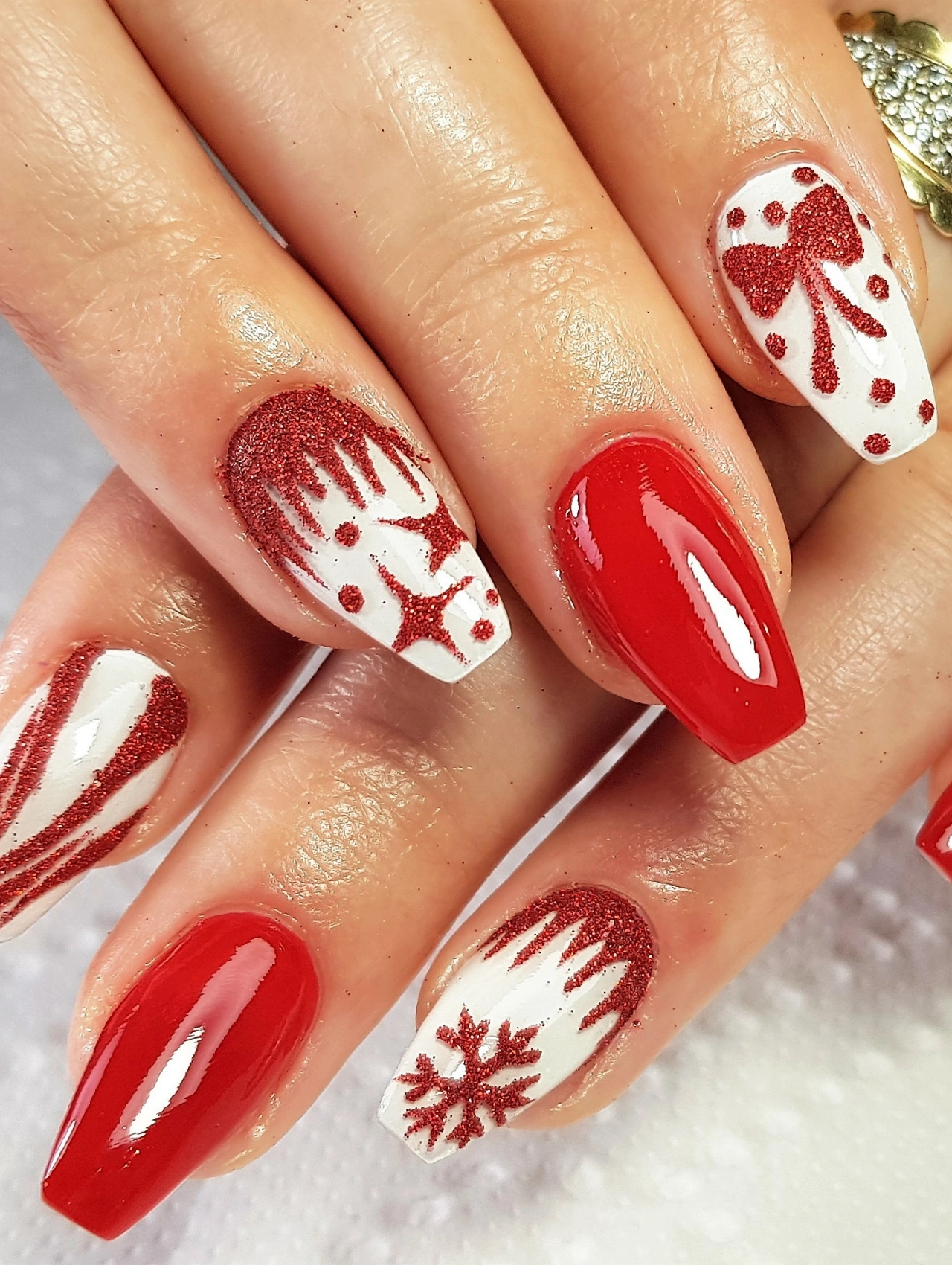 Various Christmas Nail design featuring red glitter bows, candy cane stripes, and snowflake accents.