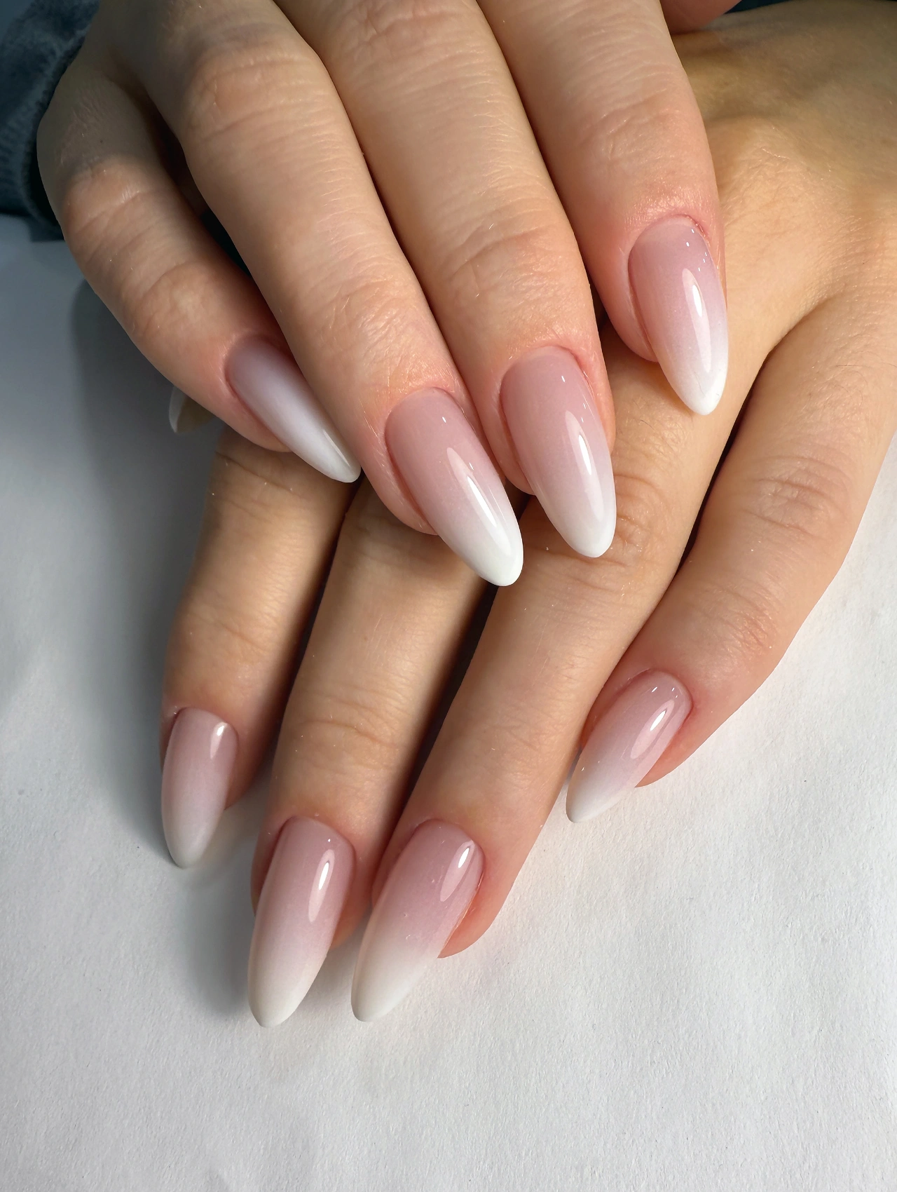 Modern Christmas Nail ombré design in soft nude and white almond-shaped acrylics.