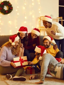 Grupo de amigos con gorros de Navidad intercambiando regalos, ejemplo de detalles para amigo secreto.