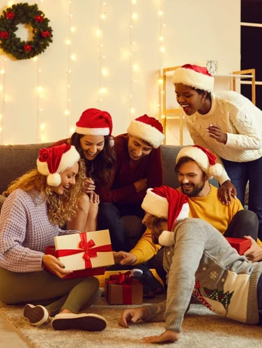 Grupo de amigos con gorros de Navidad intercambiando regalos, ejemplo de detalles para amigo secreto.