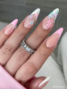 A playful pastel floral nail design featuring stiletto-shaped French tips in soft pink and white, adorned with hand-painted daisy accents.