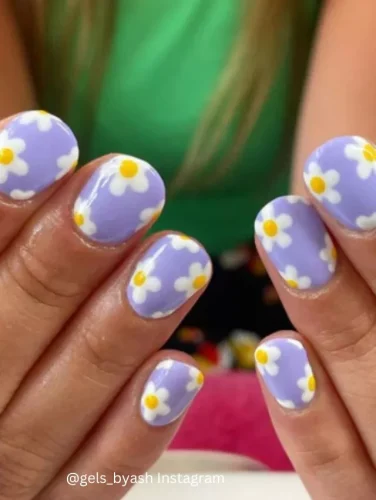 Close-up of hands displaying nails painted in a lovely lavender hue, each adorned with small white daisies with yellow centers.