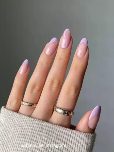 Close-up of hands displaying nails painted in a soft lilac gradient, giving the appearance of smooth, subtle waves.