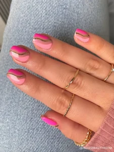 A stylish manicure featuring wavy hot pink and baby pink nail art accented with thin gold lines for an elegant and modern touch.
