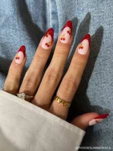 A playful and chic manicure featuring glossy red French tips adorned with delicate cherry nail art.