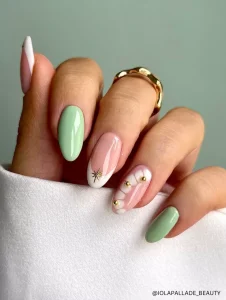 A sophisticated spring nail design featuring mint green, nude, and white tones with gold accents, floral details, and an elegant starburst embellishment.