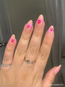 A soft nude base with delicate hot pink and magenta floral accents, creating a fresh and minimal spring-inspired manicure.