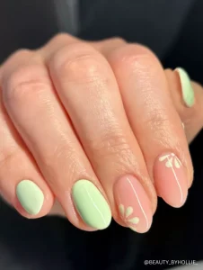 A delicate mix of soft green and peach nails featuring minimalist white floral accents, perfect for a fresh and stylish spring look.