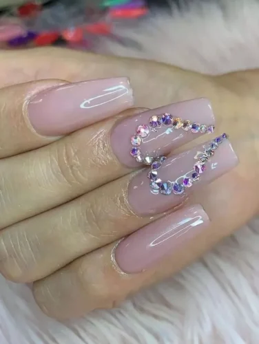 A stunning nude-pink Valentine's nail design featuring a glossy, seamless finish with an extravagant rhinestone embellishment. The sparkling crystals form a heart-shaped swirl, adding a touch of luxury and sophistication. Perfect for those who want to combine romance with a glamorous statement! Ideal for date nights, special occasions, or anyone who loves a dazzling look.