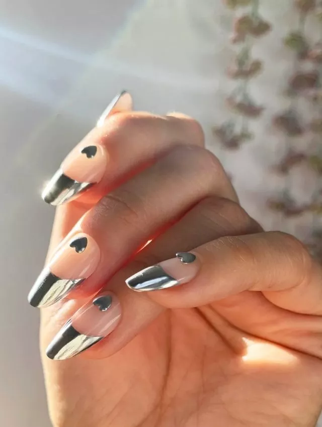 A futuristic take on Valentine's nails, this design features sleek metallic chrome French tips paired with delicate black heart accents. The nude base enhances the modern aesthetic, creating a chic contrast. Perfect for trendsetters who love a minimalist yet edgy look with a romantic touch! Ideal for stylish date nights or a bold fashion statement.