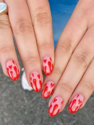 This daring and artistic Valentine's nail design features a unique red drip effect cascading from the tips, creating a bold and edgy look. Tiny heart accents scattered throughout the design add a romantic twist to the fiery aesthetic. The glossy finish enhances the vibrant red color, making it a standout choice for those who love a mix of passion and creativity in their nail art. Perfect for making a statement on Valentine's Day!