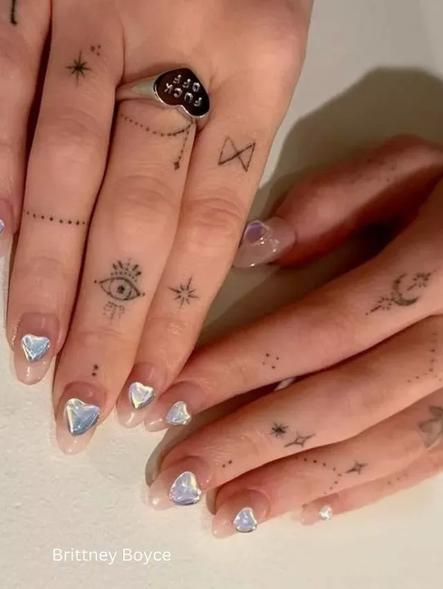 A modern and edgy take on Valentine's nails, featuring a translucent nude base adorned with stunning iridescent 3D heart embellishments. The reflective crystal-like hearts add a luxurious and futuristic vibe, making this design perfect for those who love a minimal yet striking look. Paired with delicate hand tattoos and statement rings, this style is effortlessly cool and chic! 💎✨