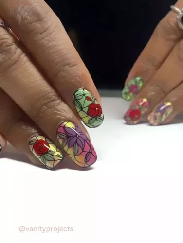 A mesmerizing and artistic nail design inspired by the beauty of stained glass art. This intricate manicure features delicate floral patterns in vivid red, purple, and yellow hues, outlined with fine black detailing for a striking effect. The gradient pastel background enhances the illusion of light filtering through glass, giving these nails an elegant and unique touch. Perfect for those who love bold, artistic statements with a romantic twist. 🌸✨