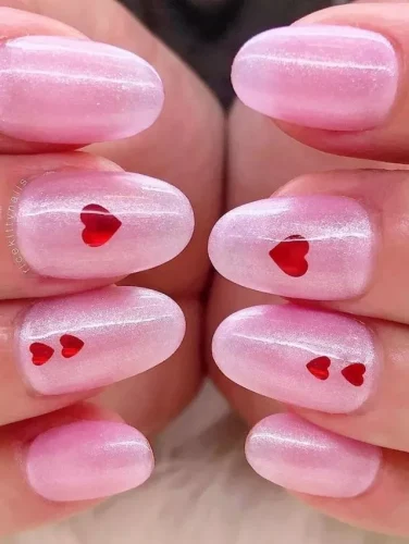 Este diseño muestra una base rosa suave y brillante, infundida con una sutil iridiscencia que capta la luz maravillosamente, creando una estética soñadora y romántica. Pequeños y precisos recortes en forma de corazón revelan un tono rojo más profundo debajo, añadiendo un toque de intriga y profundidad al aspecto general. Ideal para aquellos que prefieren su estilo de San Valentín con un toque de sofisticación juguetona, este diseño fusiona símbolos clásicos con un toque contemporáneo.