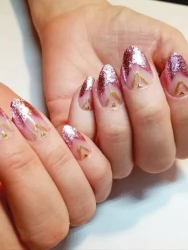 Este deslumbrante diseño de uñas presenta una transición ombré impecable desde una base nude hasta unas puntas con purpurina en oro rosa, creando un efecto degradado lujoso. Delicados acentos en chevrón dorado añaden un toque geométrico, realzando la elegancia y sofisticación del look. Perfecto para quienes aman una combinación de glamour y refinamiento, este diseño irradia una estética de alta costura, convirtiéndolo en una opción ideal para celebraciones de San Valentín o eventos exclusivos.