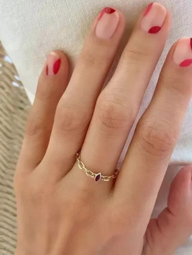 Este diseño de uñas minimalista presenta una base nude translúcida adornada con delicados acentos abstractos en rojo, creando un look moderno y discreto para San Valentín. Los diminutos detalles rojos, estratégicamente colocados cerca de las puntas y bordes, imitan suaves pinceladas románticas, ofreciendo una estética elegante sin esfuerzo. Perfecto para quienes aprecian la sutileza con un toque artístico, este diseño complementa cualquier estilo mientras mantiene un encanto refinado y sofisticado.