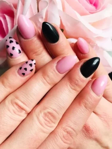 Este moderno diseño de uñas fusiona la suavidad del romance con un audaz contraste, combinando tonos de rosa pastel, negro intenso y adorables acentos de corazones. Las uñas almendradas en negro y rosa alternan para agregar dimensión, mientras que los detalles con patrones de corazones aportan un toque coqueto y divertido para San Valentín. Perfecto para quienes buscan un equilibrio entre encanto juguetón y sofisticación audaz, esta manicura es una declaración de amor con un giro rebelde.