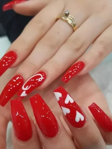 Un impresionante y audaz diseño de uñas para San Valentín, con uñas en forma de ataúd rojo brillante adornadas con delicados acentos de corazones blancos y detalles románticos en espiral. El acabado de alto brillo añade un toque ultra glamuroso, haciendo que estas uñas sean perfectas para una declaración apasionada y confiada. ¡Ideal para quienes aman el clásico rojo con un giro moderno lleno de amor!