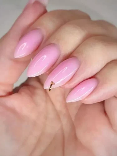 Estas uñas almendradas de alto brillo presentan un suave degradado rosa para un look romántico y elegante. ¿El detalle destacado? Un piercing con anillo dorado en el dedo anular, añadiendo un toque audaz pero sofisticado. ¡Perfecto para quienes aman la belleza clásica con un toque de rebeldía!