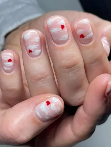 Estas soñadoras uñas cortas presentan una suave base rosa translúcida con delicados acentos de nubes blancas, creando un efecto ligero y etéreo. Pequeños detalles de corazones rojos flotan a través del diseño, creando una estética caprichosa y romántica. Perfecto para un look de uñas creativo pero sutil para el Día de San Valentín que se siente fresco y etéreo.