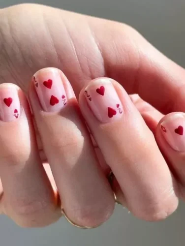 El diseño "dispersión de cariños" adopta un enfoque juguetón y entrañable para el arte de uñas de San Valentín. Cuenta con una base rosa transparente que otorga un brillo natural y saludable a las uñas, adornada con una dispersión aleatoria de pequeños corazones rojos en varios tamaños y orientaciones.

Este diseño es perfecto para aquellos que prefieren un look más discreto pero festivo, adecuado tanto para citas románticas como para reuniones informales de San Valentín. Es una elección encantadora para cualquiera que ame un toque de capricho en su estilo.