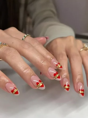 Estas impresionantes uñas para el Día de San Valentín presentan una suave base nude con puntas en forma de corazón rojo, elegantemente envueltas en un acento de cinta dorada para un efecto de regalo. Los delicados detalles blancos añaden un toque encantador, haciendo que esta manicura sea la combinación perfecta de sofisticación y romance. Ideal para quienes quieren celebrar el amor con un diseño de uñas lujoso y estiloso.