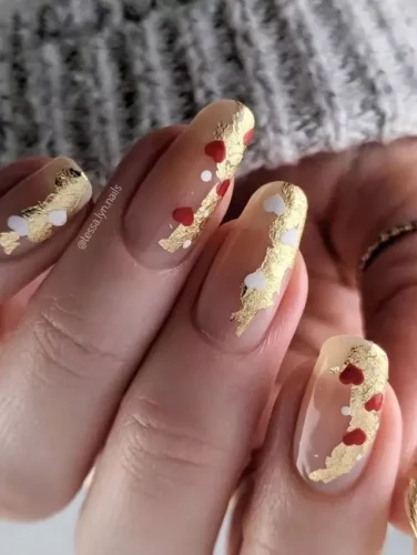 Este lujoso diseño de uñas para el Día de San Valentín presenta delicados acentos de lámina dorada sobre una base nude translúcida, creando un look refinado y elegante. Pequeños corazones rojos y blancos se dispersan a lo largo del diseño, añadiendo un toque romántico mientras mantiene una estética sofisticada. Perfecto para quienes aman la combinación de minimalismo y opulencia, esta manicura es una verdadera declaración de amor y lujo.