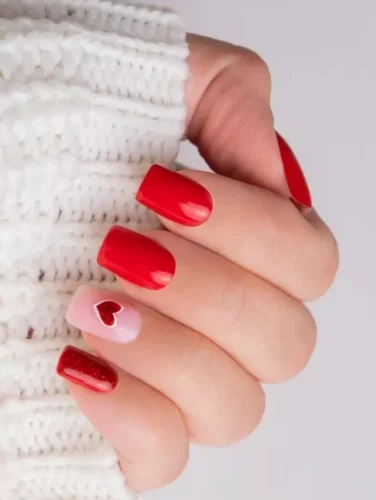 Un diseño atemporal de uñas para San Valentín, con audaz esmalte rojo brillante complementado por una suave uña de acento rosa adornada con un delicado corazón rojo. La adición de una uña roja con purpurina agrega un toque de brillo, haciendo que este look sea tanto elegante como romántico. Perfecto para quienes aman una manicura clásica pero estilosa para San Valentín.