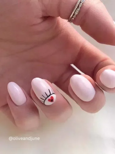 Una manicura rosa suave con un giro juguetón y romántico. Este arte de uñas presenta un delicado diseño de ojo cerrado con un pequeño corazón rojo como pupila, simbolizando el amor y el afecto a primera vista. El toque minimalista pero artístico lo convierte en una opción perfecta para el Día de San Valentín o para quienes aman un diseño sutil pero significativo. ¡Simple, chic y lleno de encanto!