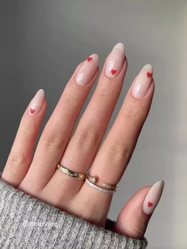 ¡Sutil pero romántico! Este diseño de uñas presenta una base ombré suave que va de nude a lechoso, con pequeños acentos de corazones rojos para un delicado toque de San Valentín. Perfecto para quienes aman una manicura simple, elegante y atemporal.