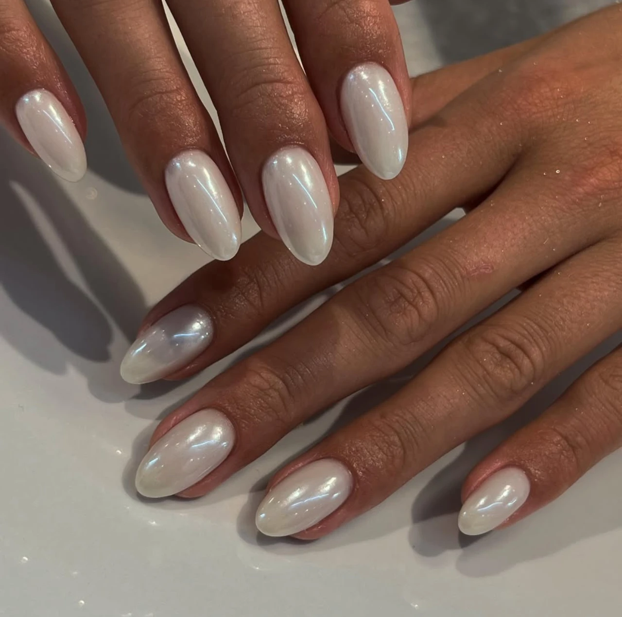 Diseño de uñas blanco perlado sofisticado con acabado brillante para nochevieja.