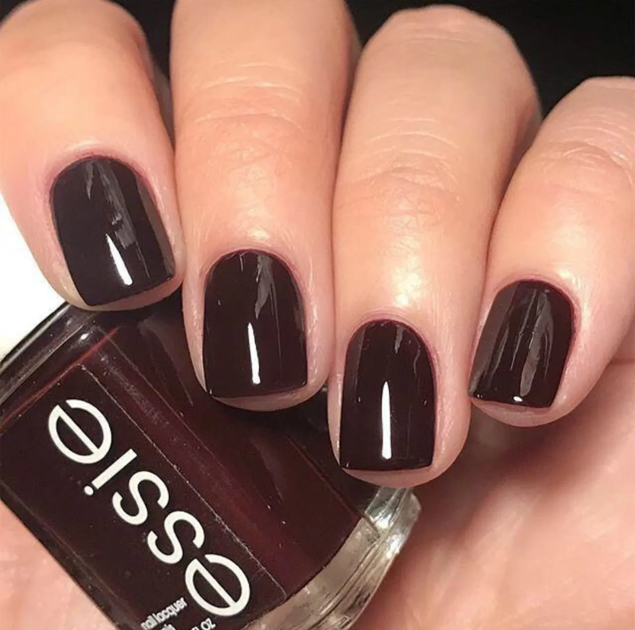 Uñas con esmalte Essie Nail Polish en Wicked, un tono burdeos profundo, ideal para los colores de uñas de invierno en tendencia.