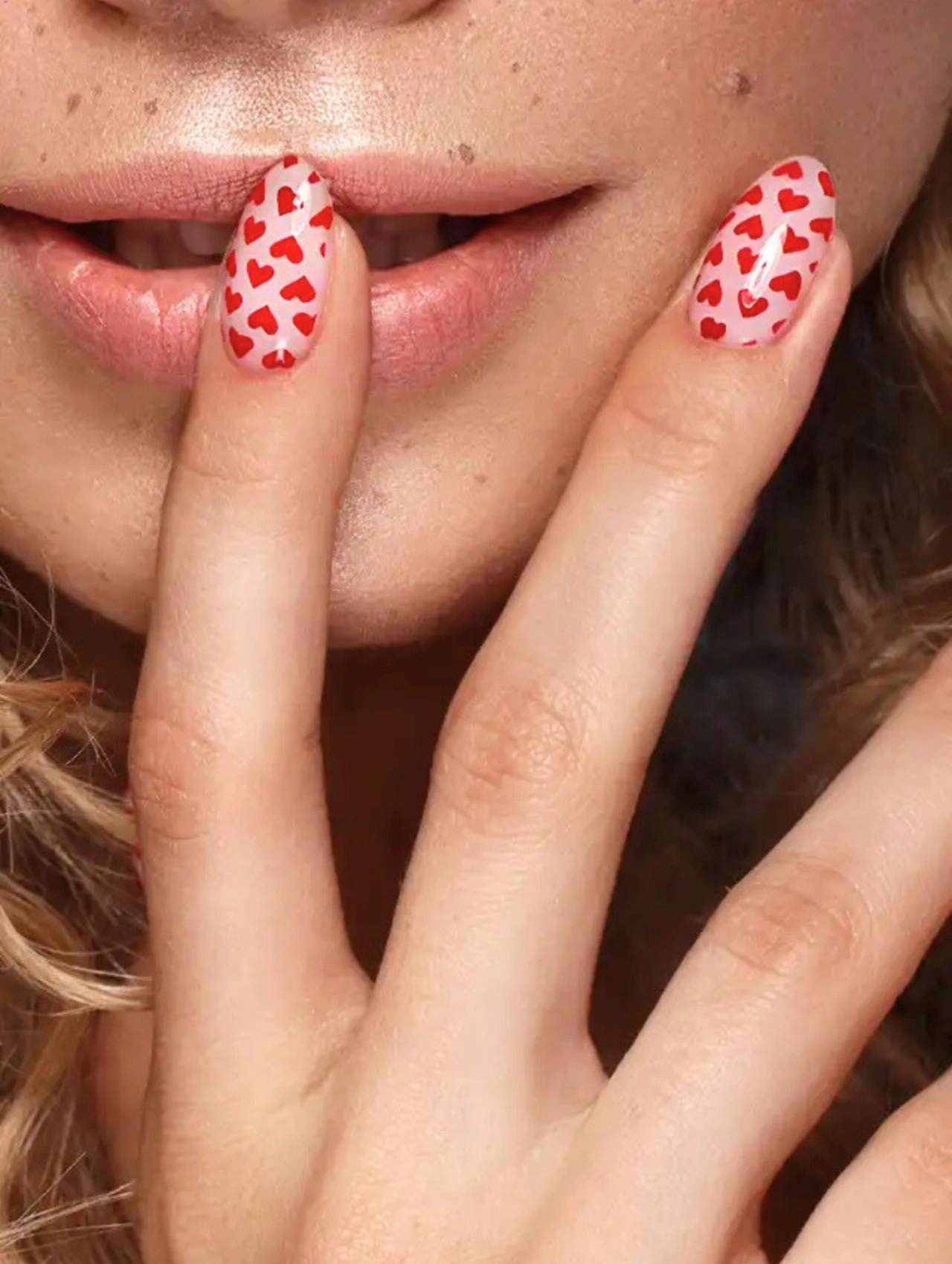 Uñas bonitas para San Valentín con diseño de corazones rojos sobre base clara, un estilo divertido y romántico para celebrar el amor.