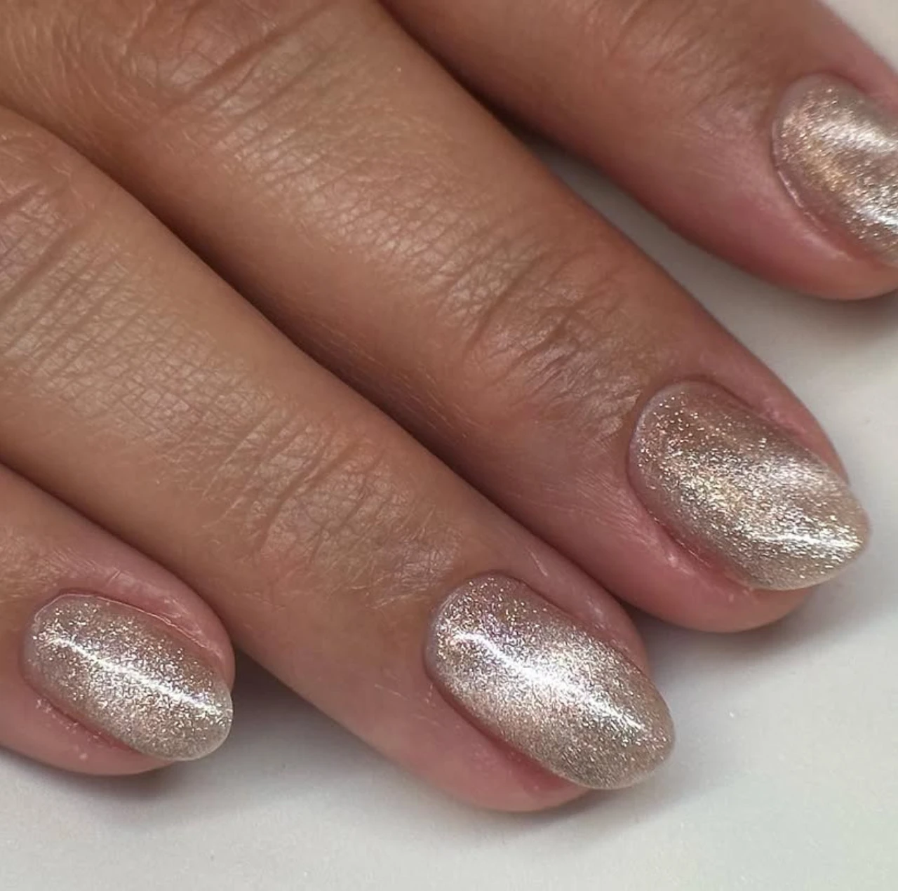 Diseños de uñas de invierno en tono champagne dorado con brillo, ideales para nochevieja.