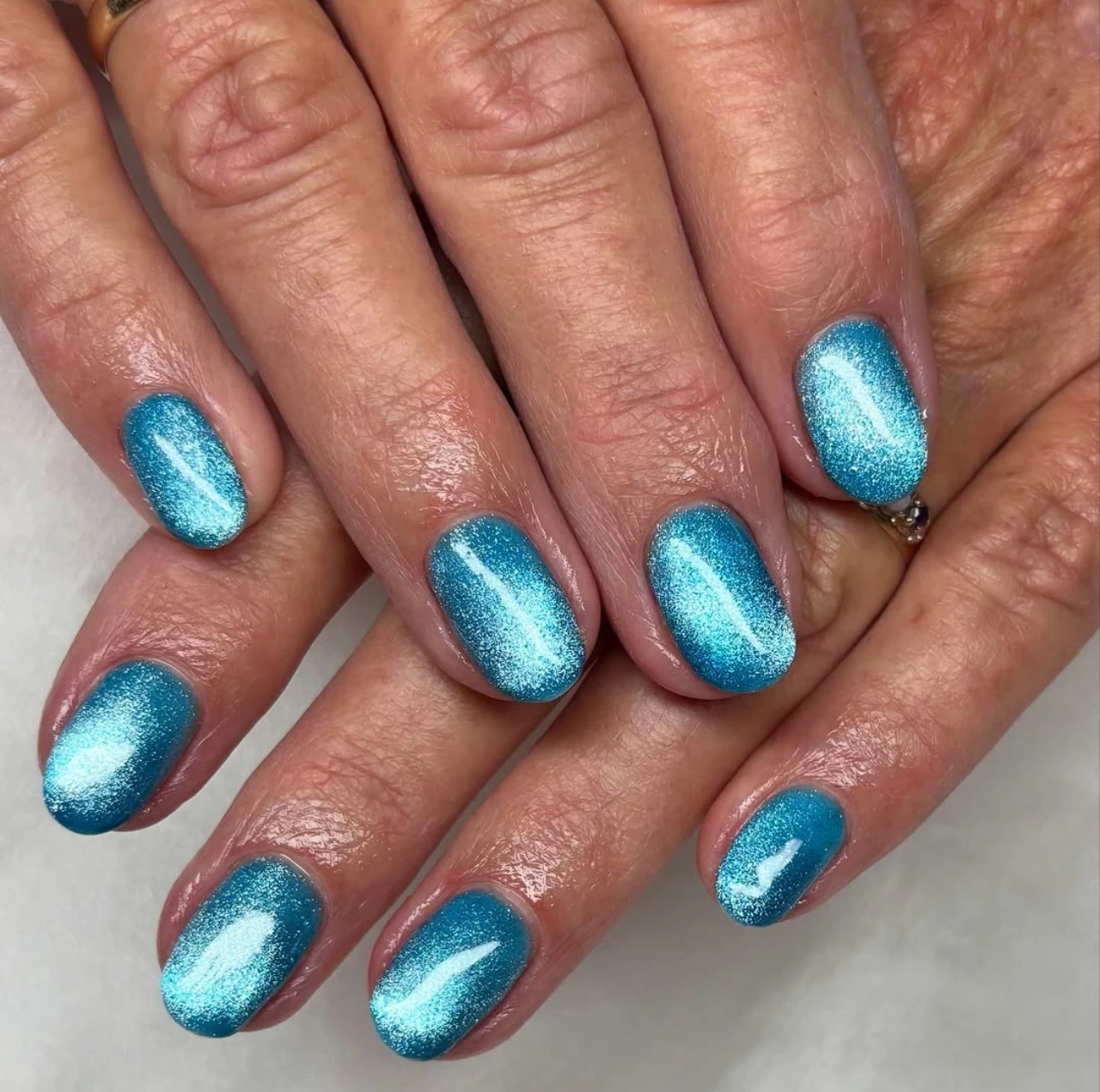 Diseños de uñas de invierno en azul aqua con efecto brillante, ideales para la temporada fría.