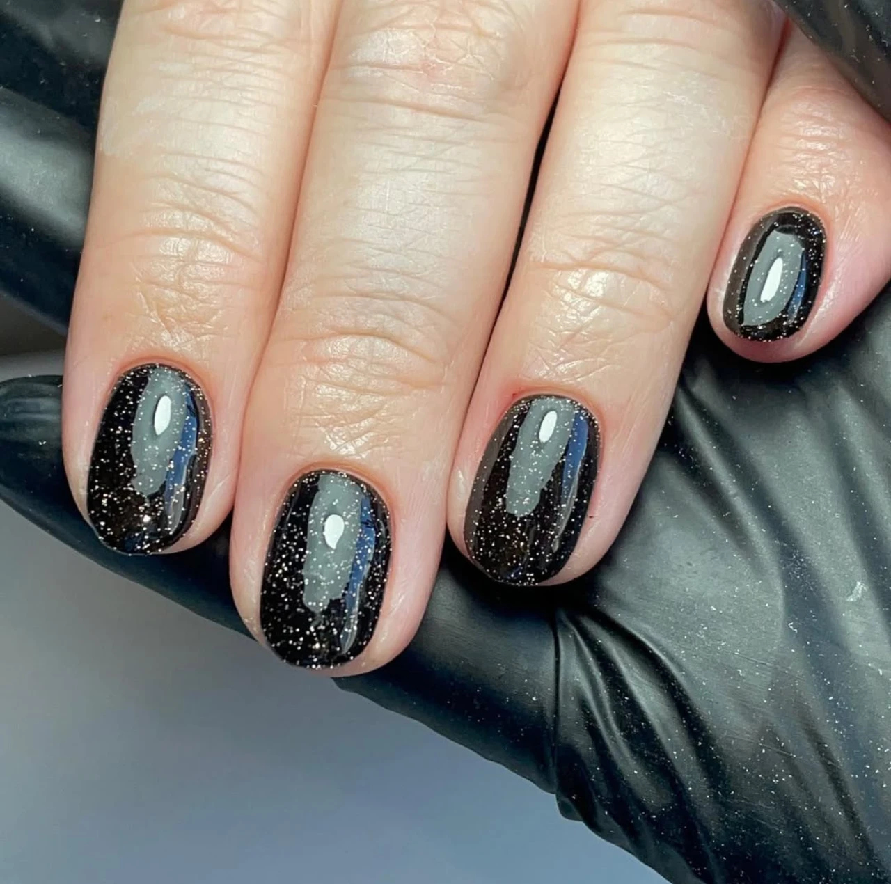 Uñas negras con brillo estilo noche para un look elegante en nochevieja.