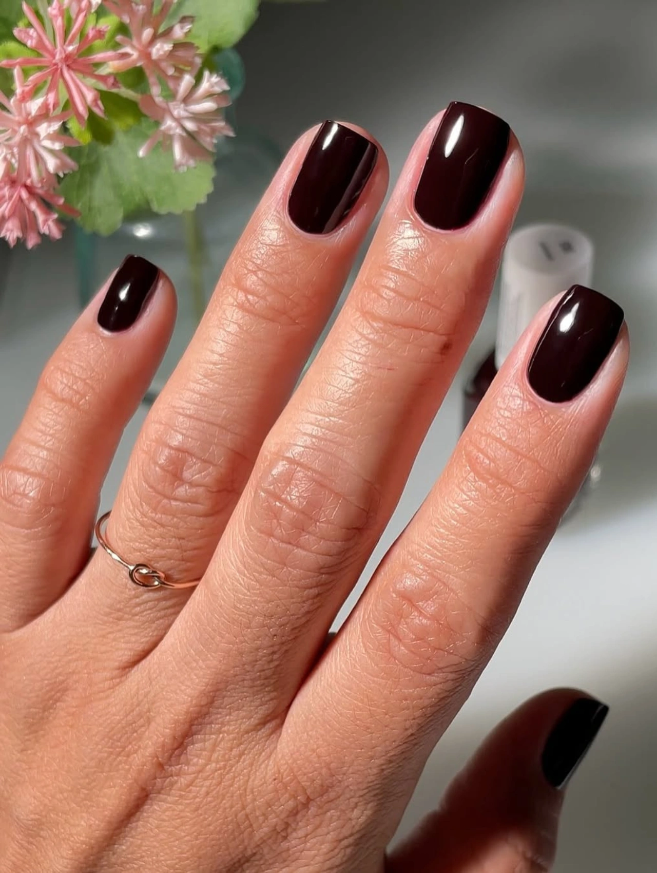 Manicura en tono ciruela oscuro con Essie Wicked, representando los colores de uñas de invierno en tendencia.