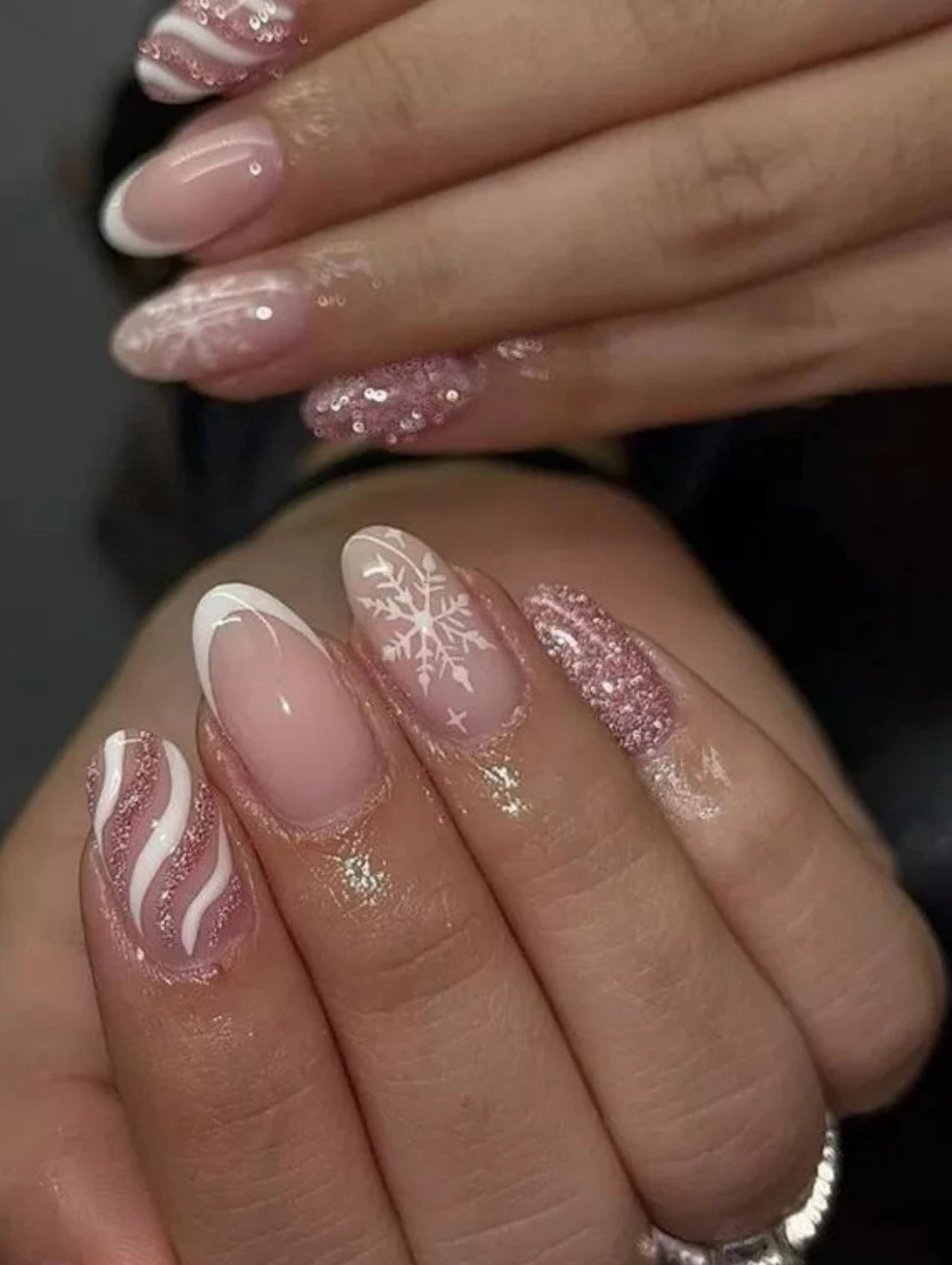 Pink frosted manicure with glitter and white snowflake accents, ideal for soft and elegant December Nails