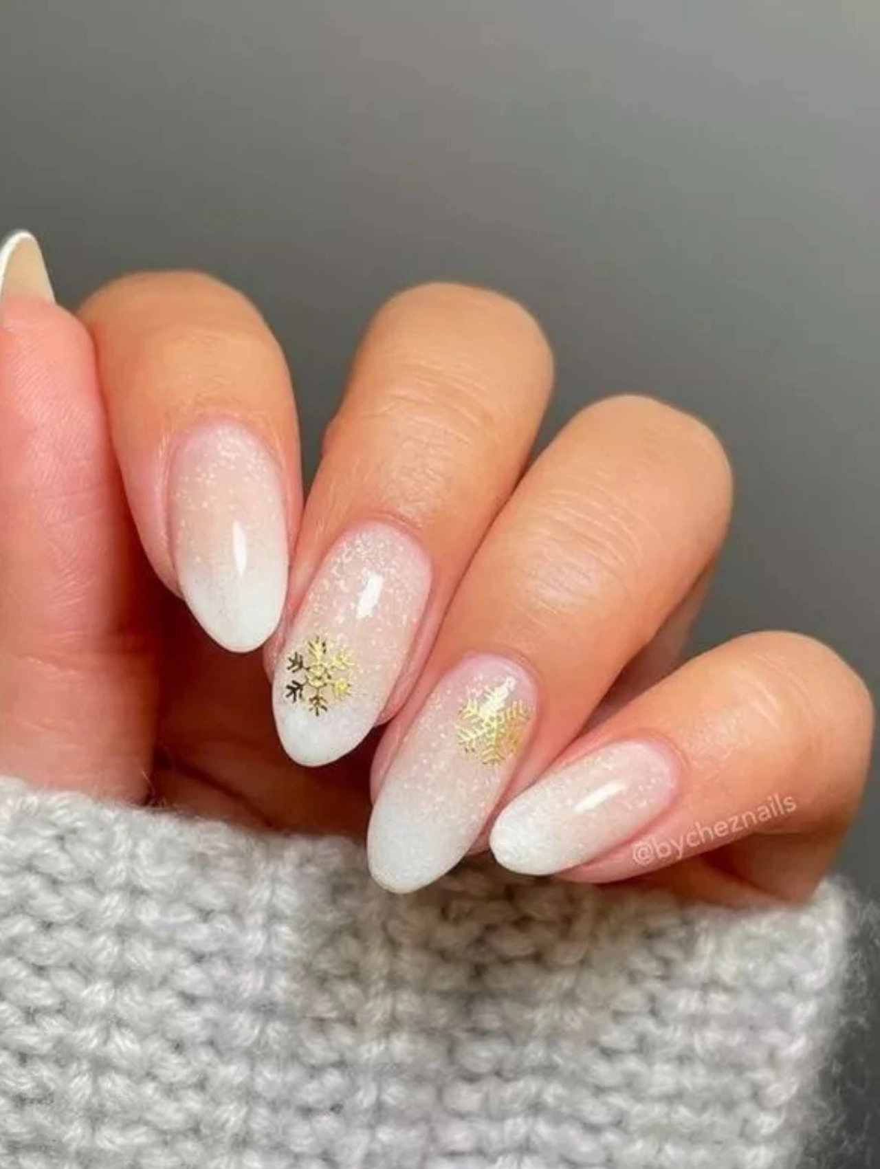 White ombré manicure with gold snowflake decals, offering elegant and warm-toned December Nails