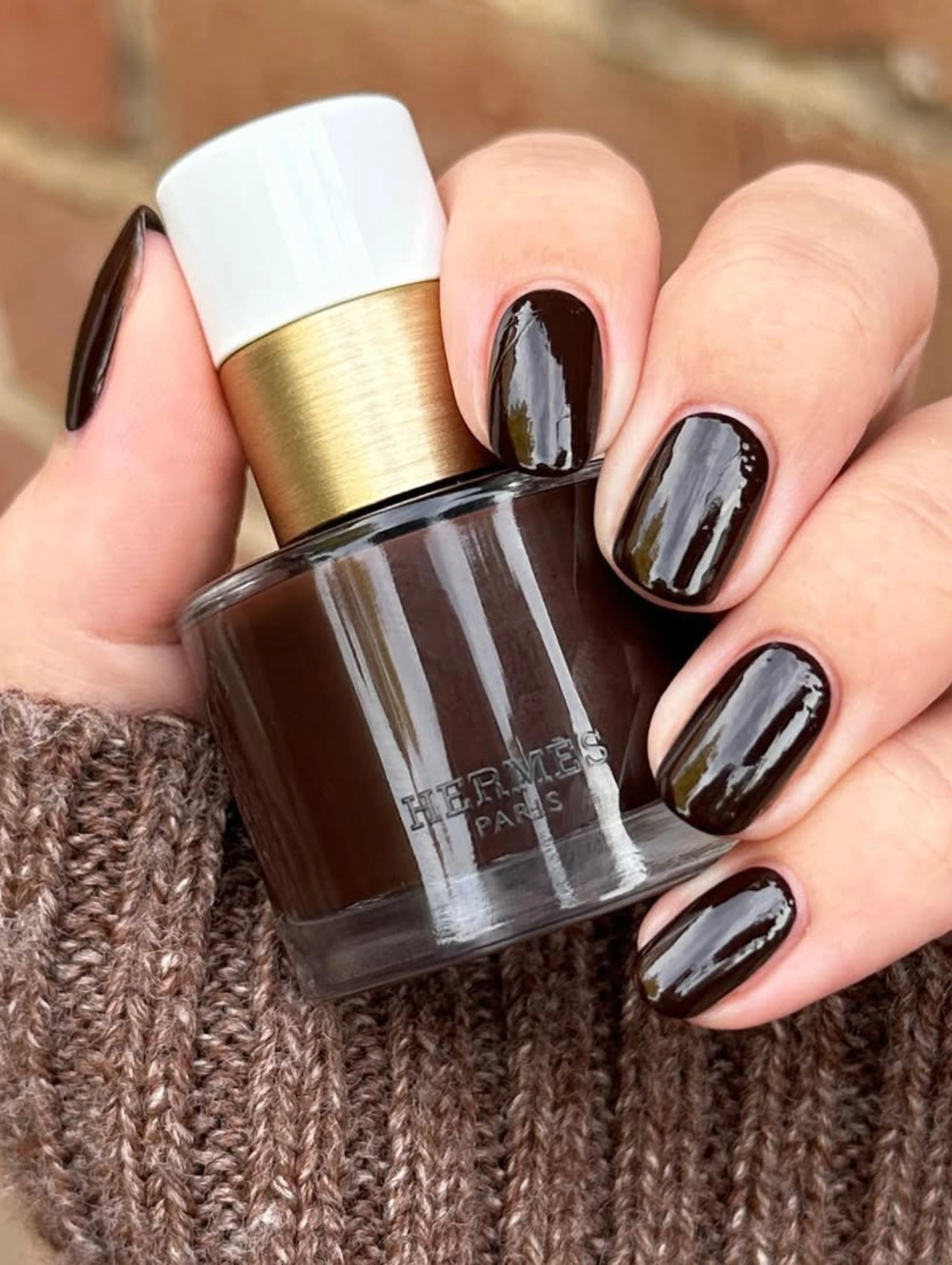 Uñas marrón chocolate con esmalte Hermès Brun Bistre, reflejando los colores de uñas de invierno en tendencia.