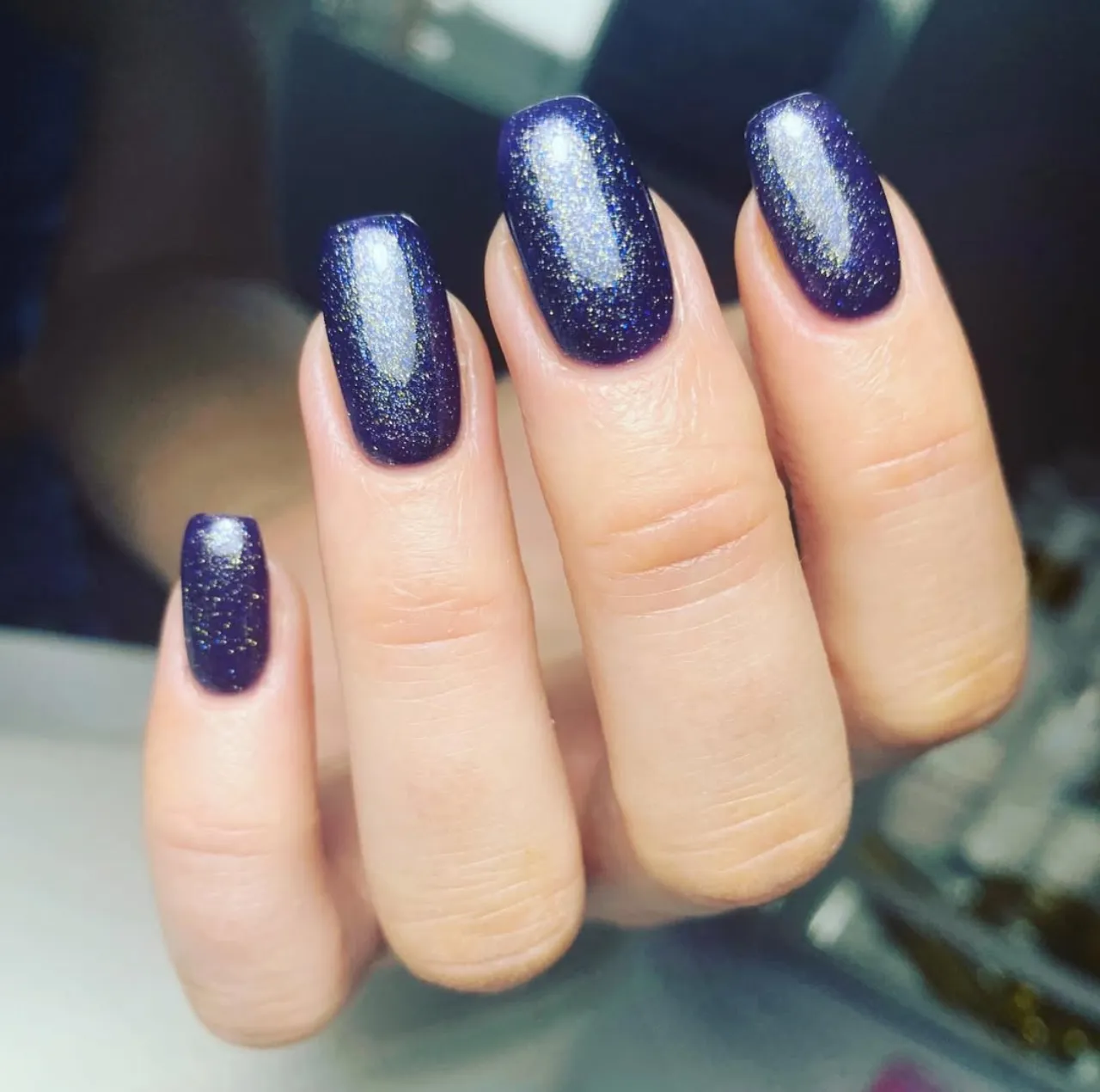 Uñas azul medianoche con acabado brillante y destellos dorados.Misterio azul medianoche: uñas que brillan con elegancia