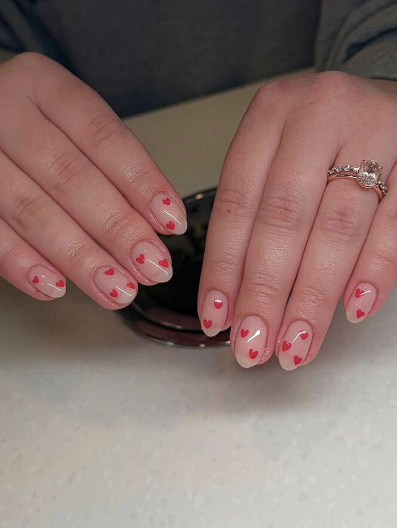 Passion Red Heart Valentines Nails Acrylic with nude acrylic nails decorated with red heart designs for Valentineโs Day.