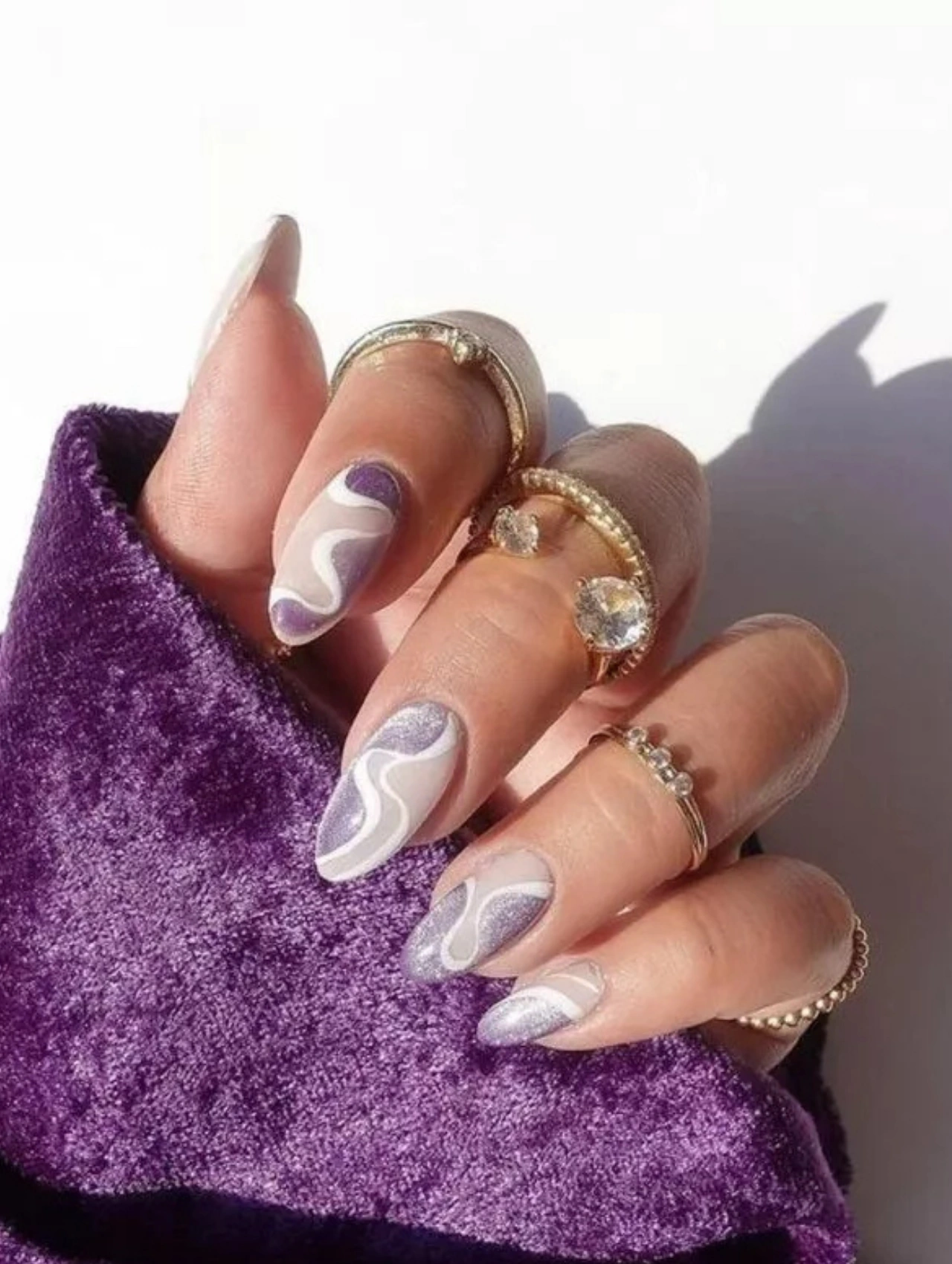 Purple swirl nail art with shimmer accents, a bold and creative option for December Nails