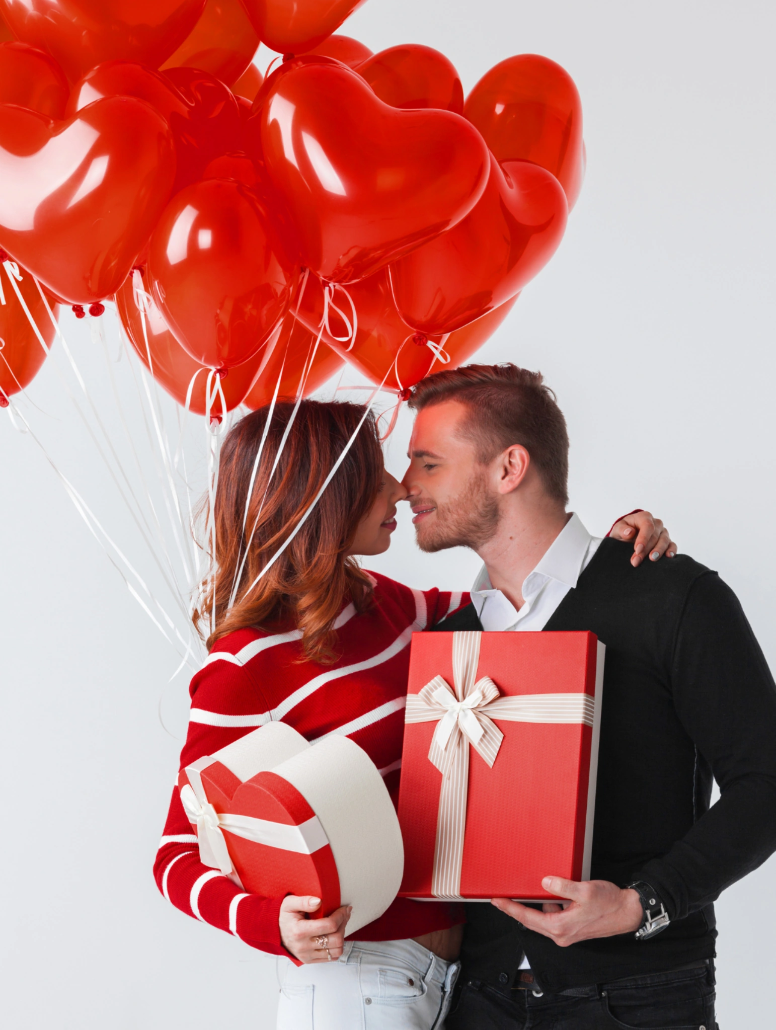 Pareja celebrando con regalos para san valentin unisex y personalizados, rodeados de globos en forma de corazón y detalles románticos.