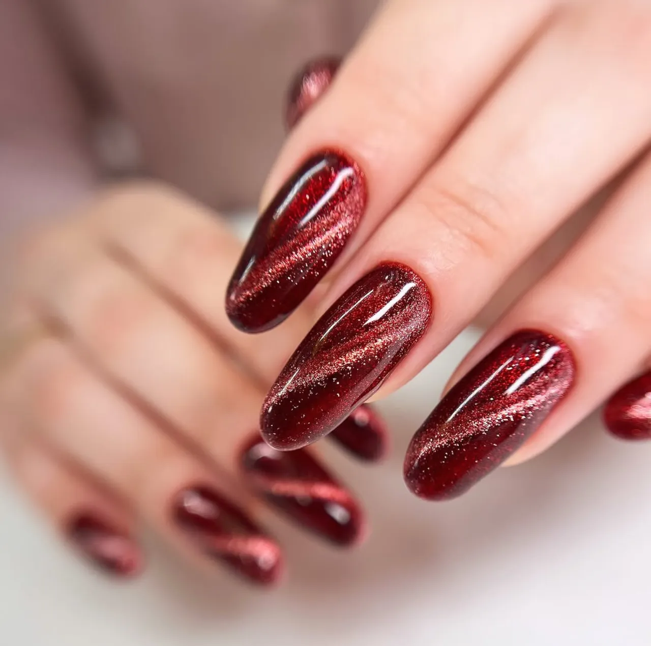 Uñas color rojo escarlata con efecto sirena y destellos brillantes.